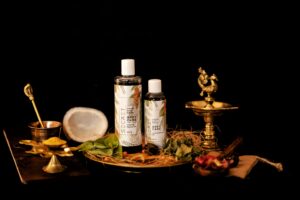 An elegant still life featuring Ayurvedic haircare oils with traditional Indian decor on a black background.